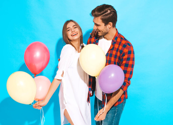 Portrait of Smiling Beautiful Girl and her Handsome Boyfriend holding bunch of colorful air balloons and laughing. Happy Family. Love. Happy Valentine's Day. Isolated on blue - Фото, изображение