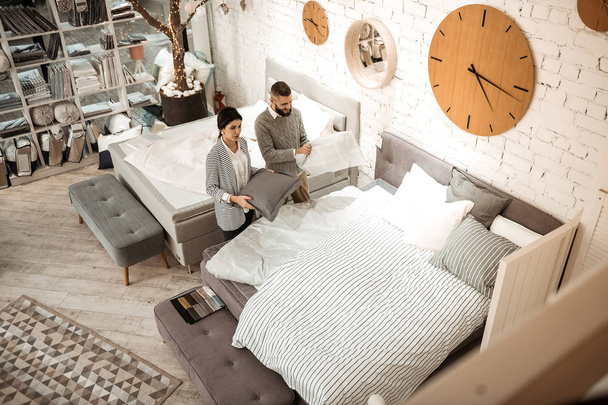 Konzentriertes Paar beobachtet Bett und Kissen im Komplex - Foto, Bild