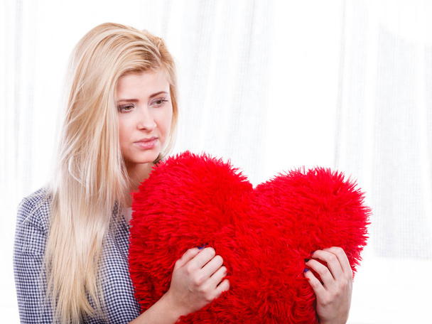 Break up, divorce, bad relationship concept. Sad, depressed woman holding big red fluffy pillow in heart shape, she needs love. - Foto, Imagen