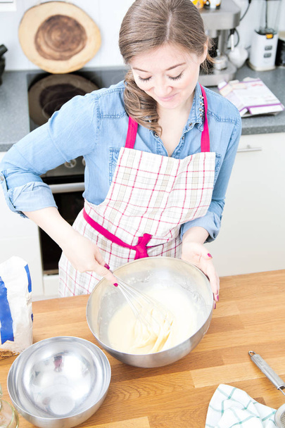 korkea kulma näkymä kaunis hymyilevä nuori nainen esiliina valmistelee taikina keittiössä
  - Valokuva, kuva