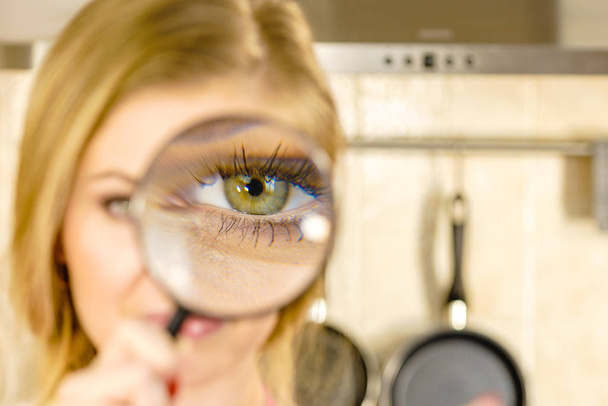 Blonde woman holding magnifying glass investigating something and looking closely, trying to find solution. - Photo, image