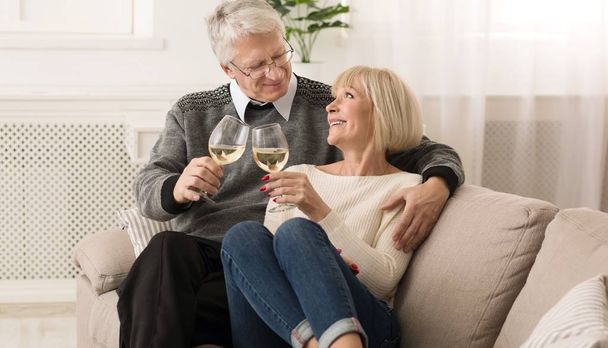 Feliz pareja de ancianos tintineo vasos de vino blanco
 - Foto, Imagen