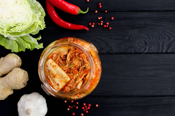Kimchi w słoik i składników na czarnym tle drewnianych. Widok z góry. Miejsce. - Zdjęcie, obraz