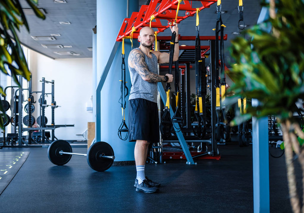 Homme sportif tatoué tenant une corde de fitness suspendue
 - Photo, image
