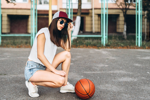 Όμορφη νεαρή σπορ κορίτσι με εξωτερική μπάλα μπάσκετ - Φωτογραφία, εικόνα