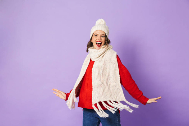 Portrait of an excited happy young woman wearing winter hat isolated over purple background. - Foto, Bild