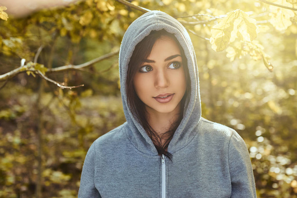 A charming girl wearing a gray hoodie in the autumn park - Photo, Image