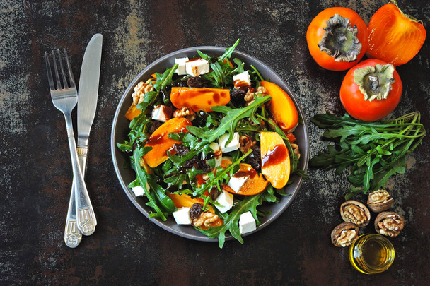 Gezonde salade met kaki, rucola, noten en feta kaas. Fitness voedsel. Superfoods vitamine herfst persimmon salade. - Foto, afbeelding