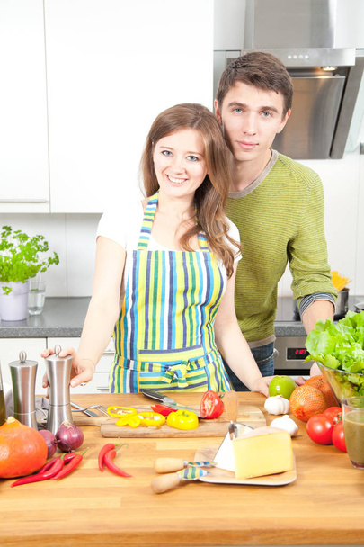 Pareja joven y feliz preparando comida saludable juntos en la cocina. Concepto de comida saludable
 - Foto, Imagen
