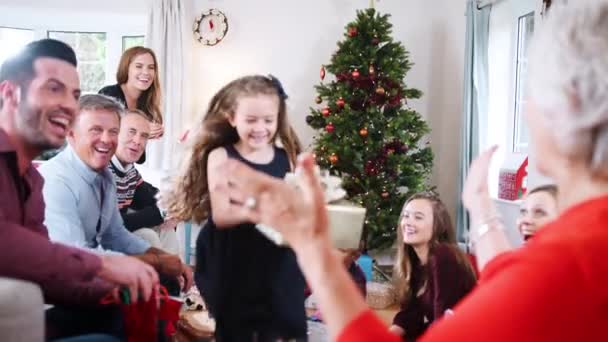 Granddaughter running towards grandmother with present as multi-generation family celebrating Christmas together - shot in slow motion - Video