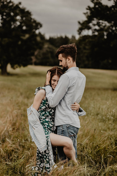 Portrait of young couple in love walking and hugging in the green field - Фото, изображение
