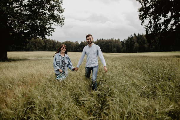 Outdoor shot of young couple walking through meadow hand in hand  - Fotoğraf, Görsel