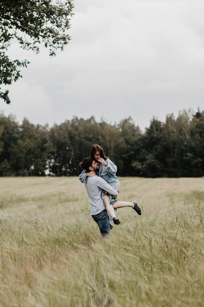 Portrait of young couple in love walking and hugging in the green field - Foto, immagini