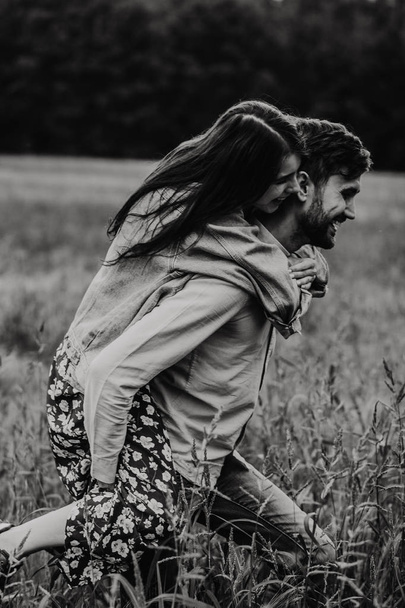 Giovane coppia innamorata che cammina e abbraccia nel prato. Foto in bianco e nero
. - Foto, immagini