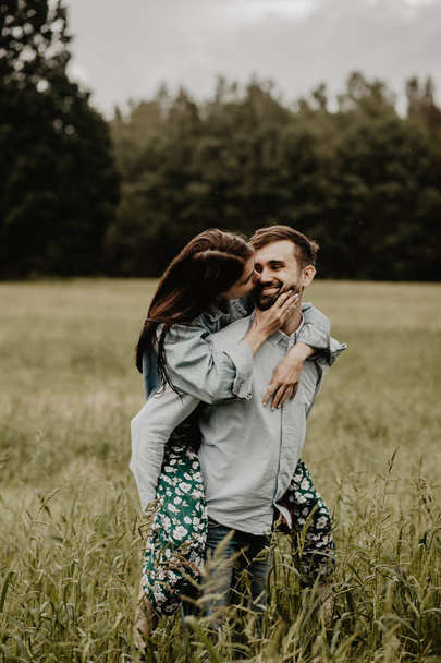 Portrait of young couple in love walking and hugging in the green field - Foto, afbeelding