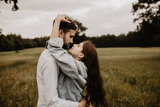 Portrait of young couple in love walking and hugging in the green field - Foto, afbeelding