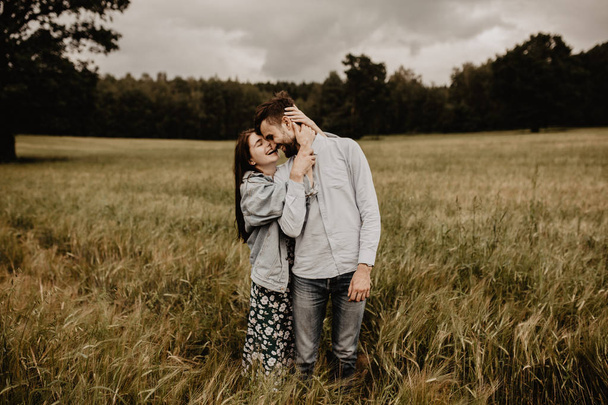 Retrato de jovem casal apaixonado caminhando e abraçando no campo verde
 - Foto, Imagem