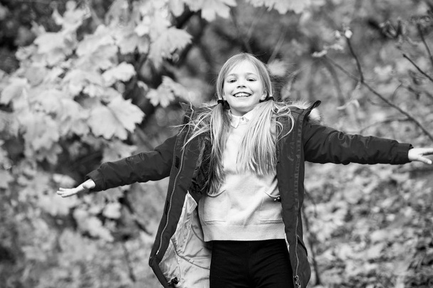 Free and happy cutie. Child blonde long hair walking in warm jacket outdoor. Girl happy in red coat enjoy fall nature park. Child wear fashionable coat with hood. Fall clothes and fashion concept. - Fotografie, Obrázek