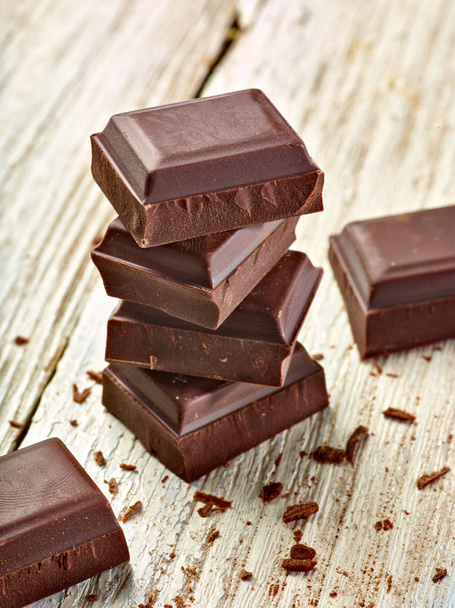 Nahaufnahme von Schokoladenstücken auf hölzernem Hintergrund - Foto, Bild