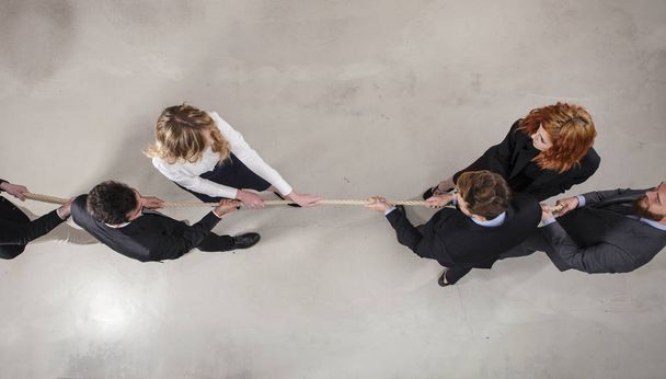 Rivalisierende Geschäftsleute wetteifern um das Kommando, indem sie am Seil ziehen - Foto, Bild