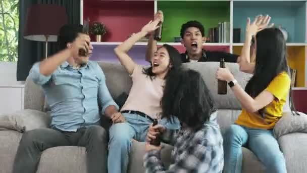 Group of friends watching tv together on sofa. Mixed race young people enjoying watching tv, cheering. House party concept. - Video
