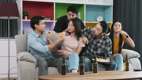 Group of happy friends is celebrating on party at home. People eating pizza and drinking beer  - Imágenes, Vídeo