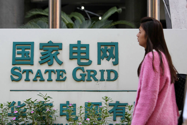 --FILE--A pedestrian walks past a branch of State Grid in Shanghai, China, 28 October 2013 - 写真・画像