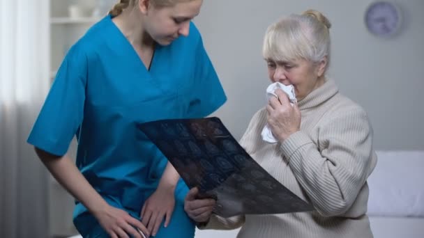 Medical worker explaining old woman x-ray examination results, diagnosis, health - Кадри, відео