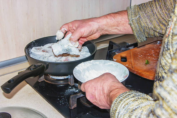 Man's hand prepare delicious pike fillets will have roasted in the frying pan. - Foto, immagini