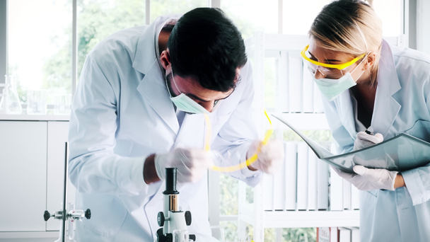 Bir laboratuarda çalışan kimyagerler grubudur. Beyaz genç erkek ve dişi kimyagerler ile mikroskop arıyorum birlikte laboratuarda, çalışan üst düzey beyaz kimyager. Bilim kavramı.  - Video, Çekim