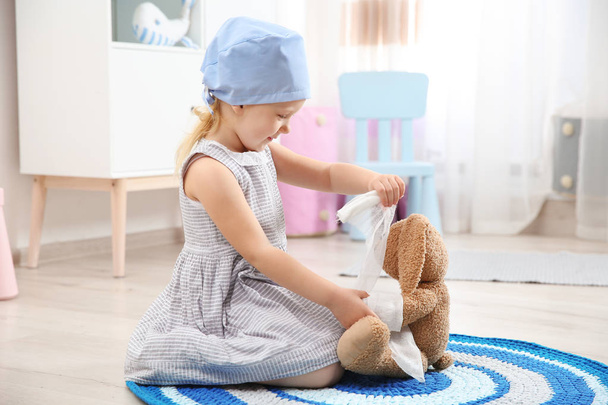 Słodkie dziecko, wyobrażając sobie siebie jako lekarz podczas gry z stetoskop i zabawka królik w domu - Zdjęcie, obraz