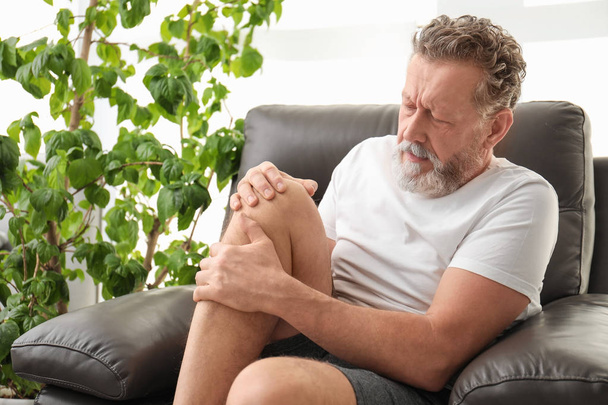 Senior man suffering from knee pain indoors - Fotoğraf, Görsel