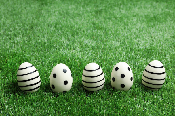 Line of traditional Easter eggs decorated with black paint on green lawn, space for text - Foto, imagen