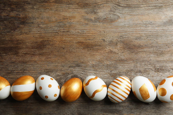 Set of traditional Easter eggs decorated with golden paint on wooden background, top view. Space for text - Foto, imagen