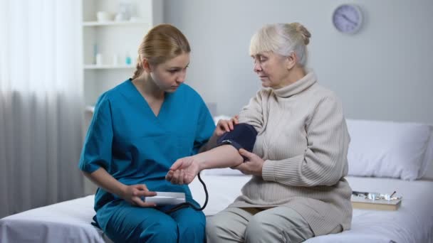 Cardiologist measuring old female patient blood pressure, professional medicare - Filmati, video