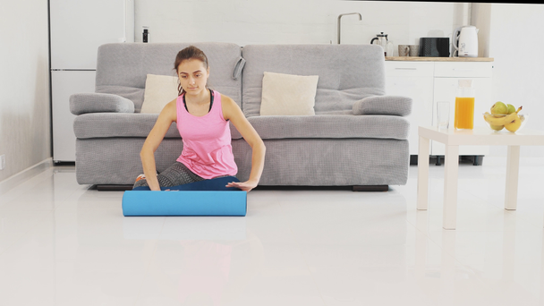 Close up of a young beautiful woman dressed in blue jogging or a fitness mat after working at home in the living room. - Filmmaterial, Video