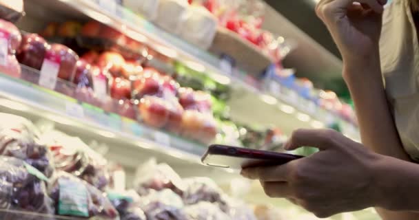 Mujer en el supermercado usando Smartphone
 - Imágenes, Vídeo