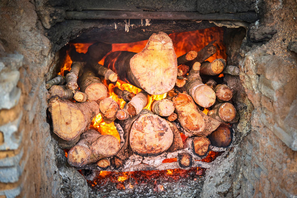 Brennende Feuerstelle mit einem Stück Brennholz, das warmes Feuer brennt  - Foto, Bild