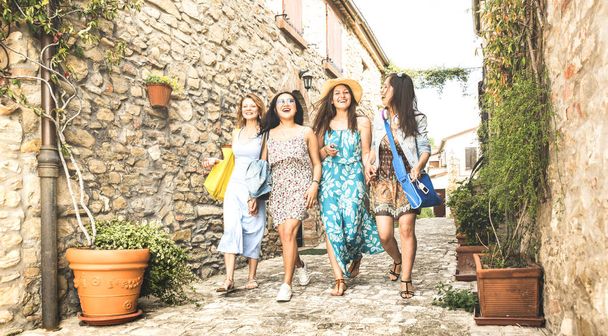 Multiracial millennial girlfriends walking in old town tour - Happy girl best friends having fun around city streets - University women students on travel vacations - Bright edsaturated vintage filter - Foto, Bild