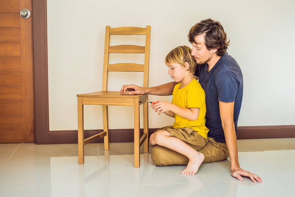 Padre e hijo ensamblando muebles. Un chico ayudando a su padre en casa. Concepto de familia feliz - Foto, imagen