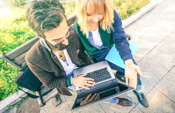 Jovem casal hipster usando laptop de computador em localização urbana ao ar livre - Conceito de diversão moderna com milênios em novas tendências e tecnologia - Conexão sem fio e internet na web redes sociais
 - Foto, Imagem