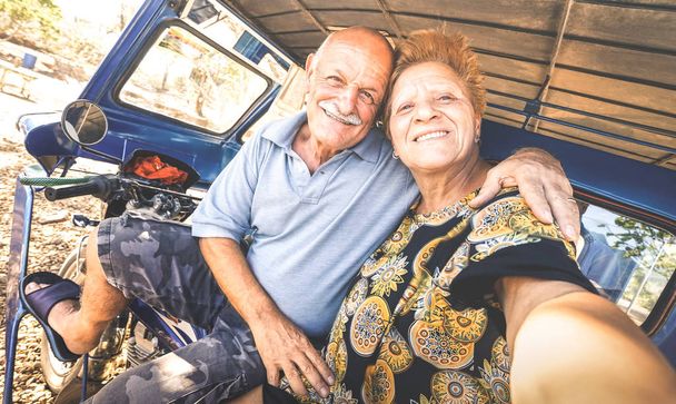 glückliches Senioren-Paar macht Selfie auf Dreirad auf den Philippinen - Konzept des aktiven, verspielten Alterns im Ruhestand - Lebensfreude ohne Altersbeschränkung - warme Nachmittagsfiltertöne - Foto, Bild