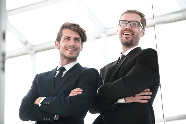 due uomini d'affari sorridenti in piedi in ufficio
 - Foto, immagini