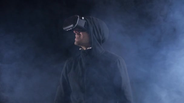 Погружение в виртуальную реальность. Человек в VR гарнитуре смотрит вокруг на черном фоне. Новые технологии и дополненная реальность
. - Кадры, видео