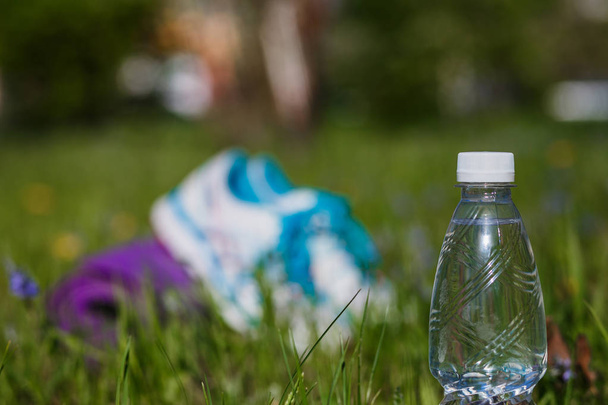 a bottle of drinking water on the grass on blurred background - Photo, image
