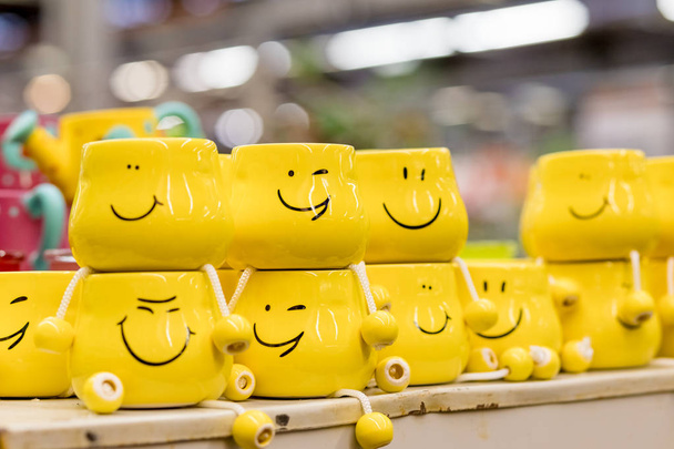 Um monte de copos amarelos com rostos engraçados no fundo borrado. O conceito de uma empresa amigável, uma grande família, encontrar amigos para uma xícara de chá ou café, dia dos pais, escritório, dia do patrão.
 - Foto, Imagem