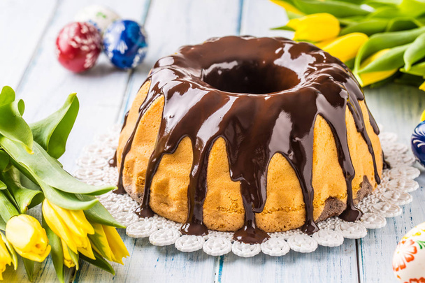 Delicious holiday slovak and czech cake babovka with chocolate glaze. Easter decorations - spring tulips and eggs. - Foto, afbeelding
