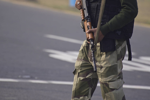 Φρουρός ασφαλείας με τουφέκι στέκεται στο εξωτερικό για να προστατεύσει την περιοχή. - Φωτογραφία, εικόνα