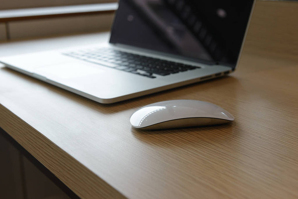 ποντίκι και το φορητό υπολογιστή στο ξύλινο γραφείο στο πατάρι του καφέ. - Φωτογραφία, εικόνα