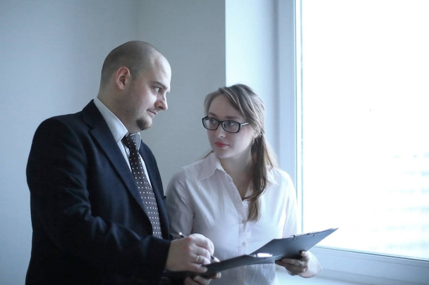 surprised businessman and assistant discussing business documents standing near office window - Foto, imagen